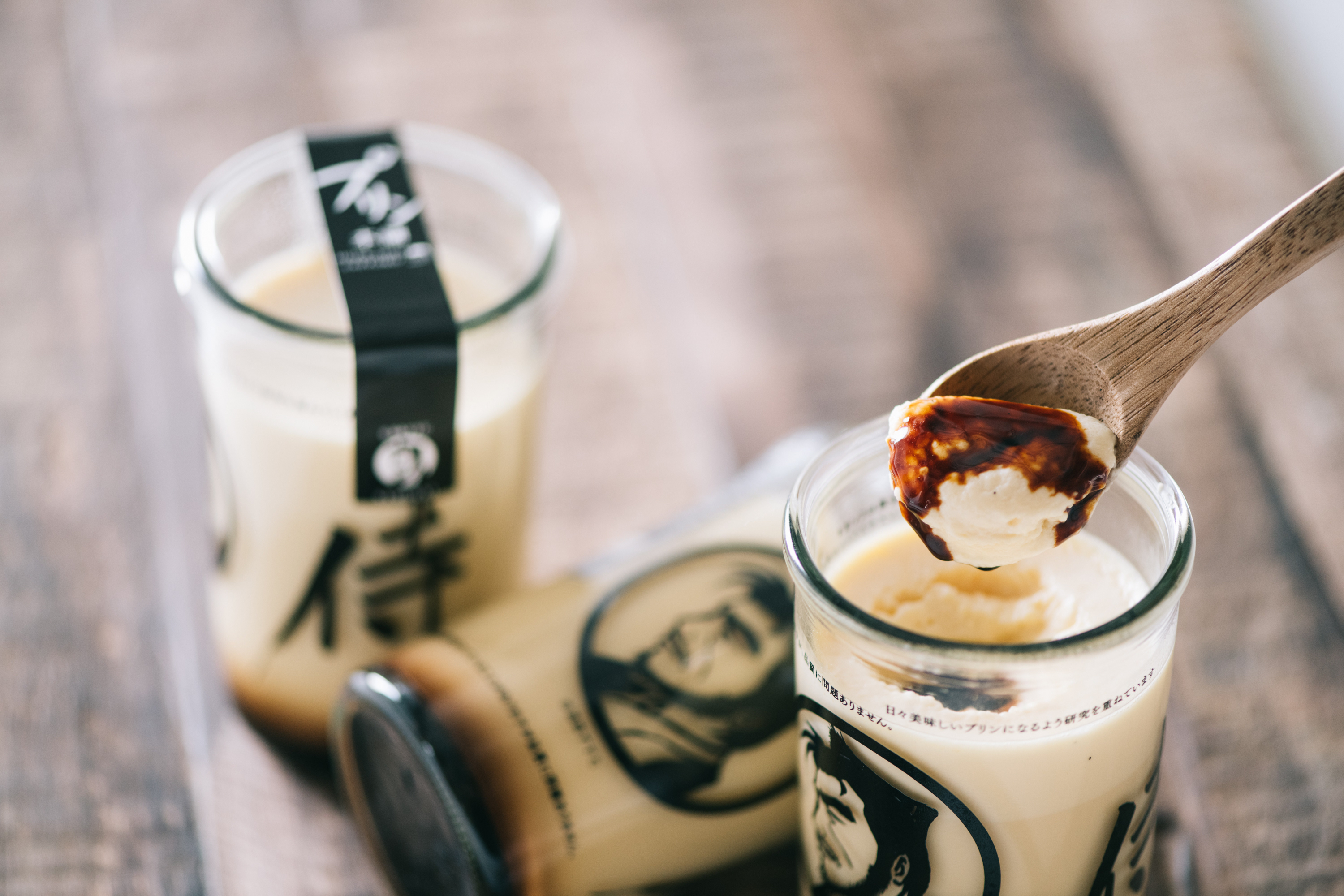 プリン本舗のプリン — 木製スプーンですくった瞬間とカラメルソース