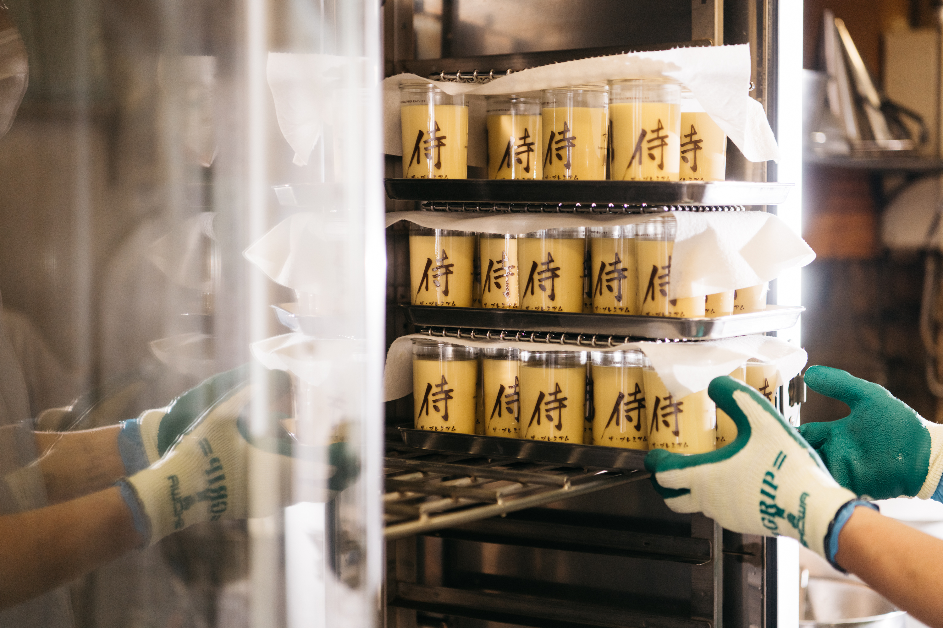 プリン本舗の製造工程 — 侍ロゴシールを職人の手で巻く